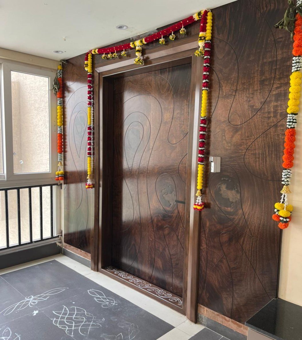 Carved walnut entrance door with floral garlands and a kolam on stone