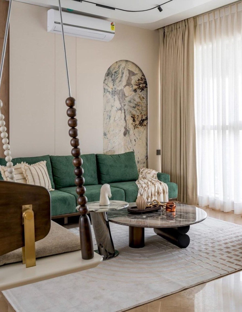 Living room with emerald sofa, marble tables, and a hanging timber swing