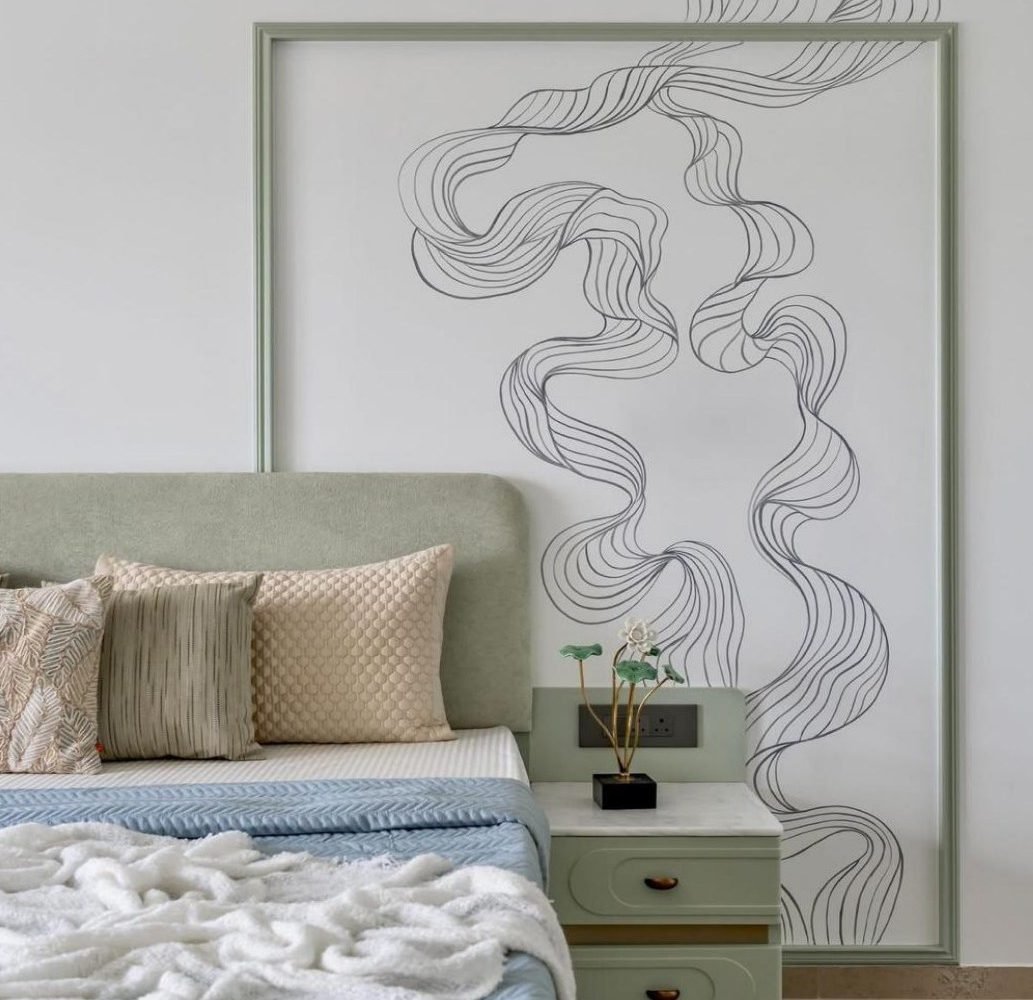 Bedroom with sage headboard, pale millwork, and a framed linear mural