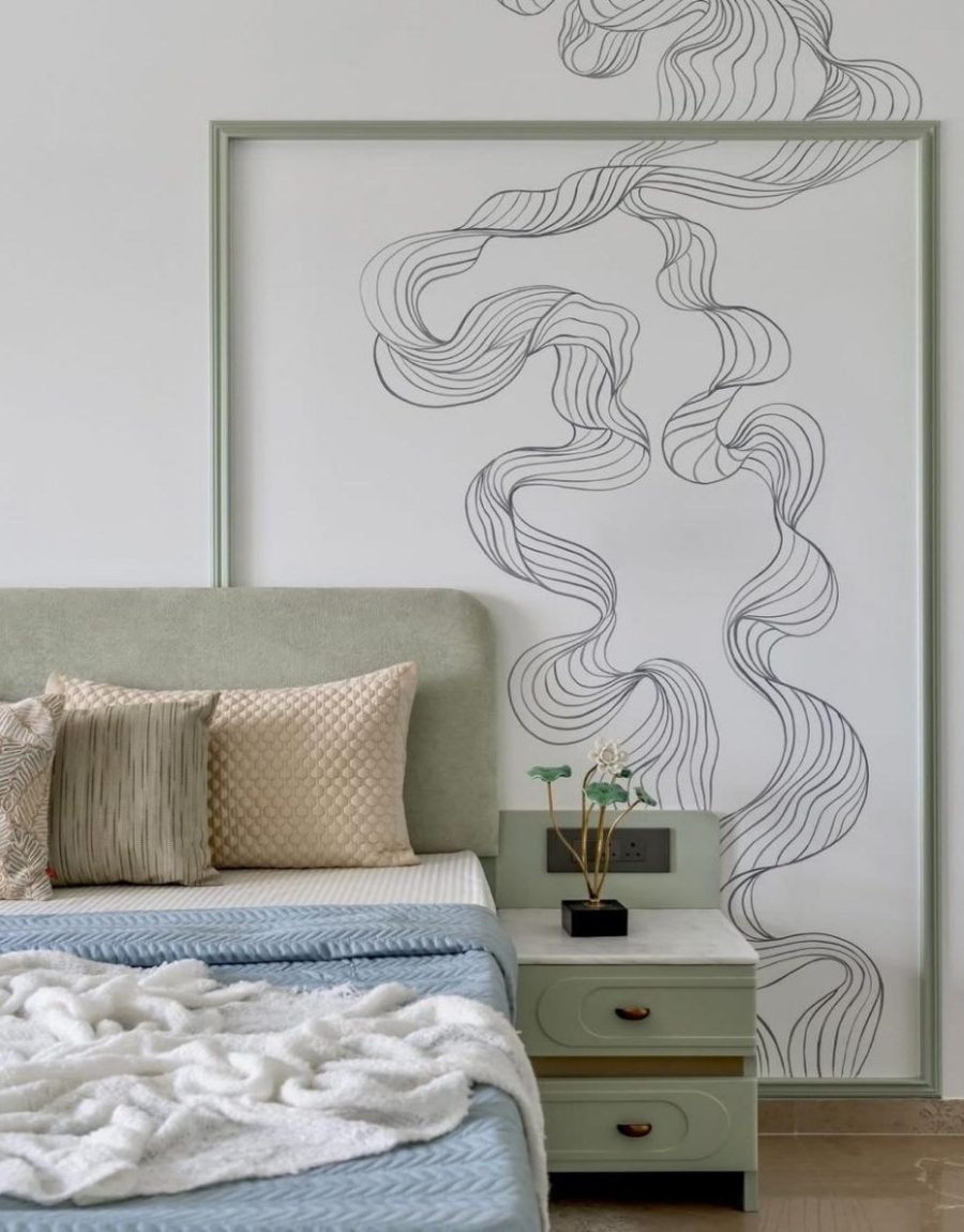 Bedroom with sage headboard, pale millwork, and a framed linear mural