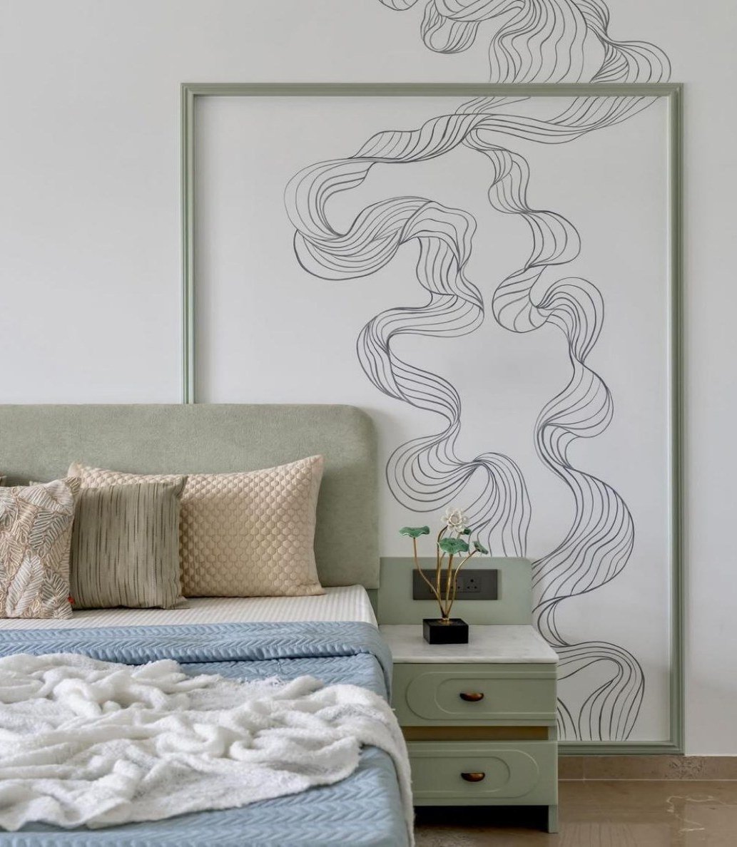 Bedroom with sage headboard, pale millwork, and a framed linear mural