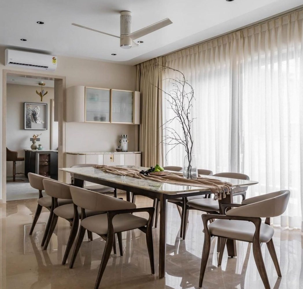 Dining room with stone table, sheer curtains, and a view to the kitchen
