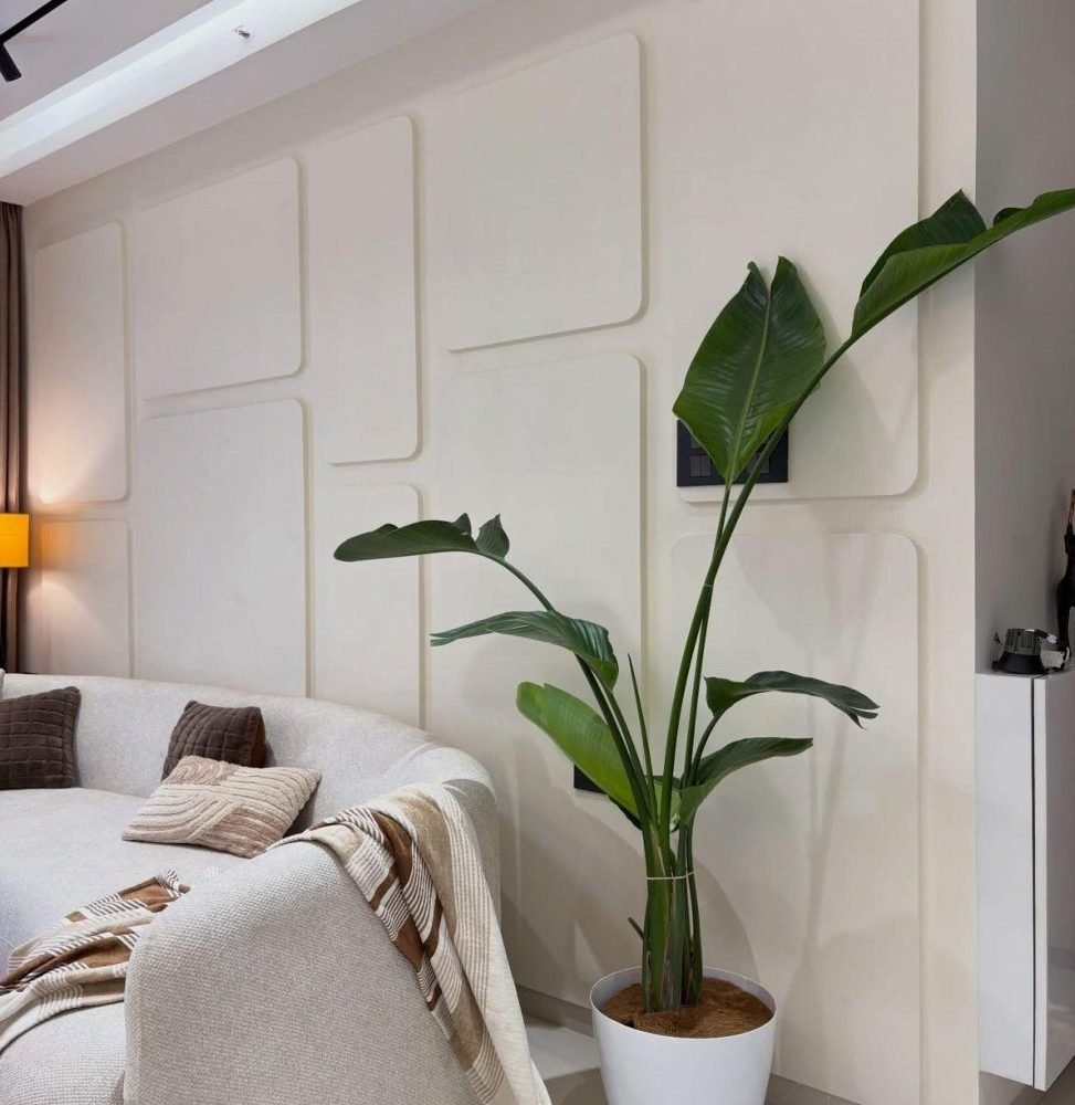 Padded wall panels and a large indoor plant beside a curved sofa
