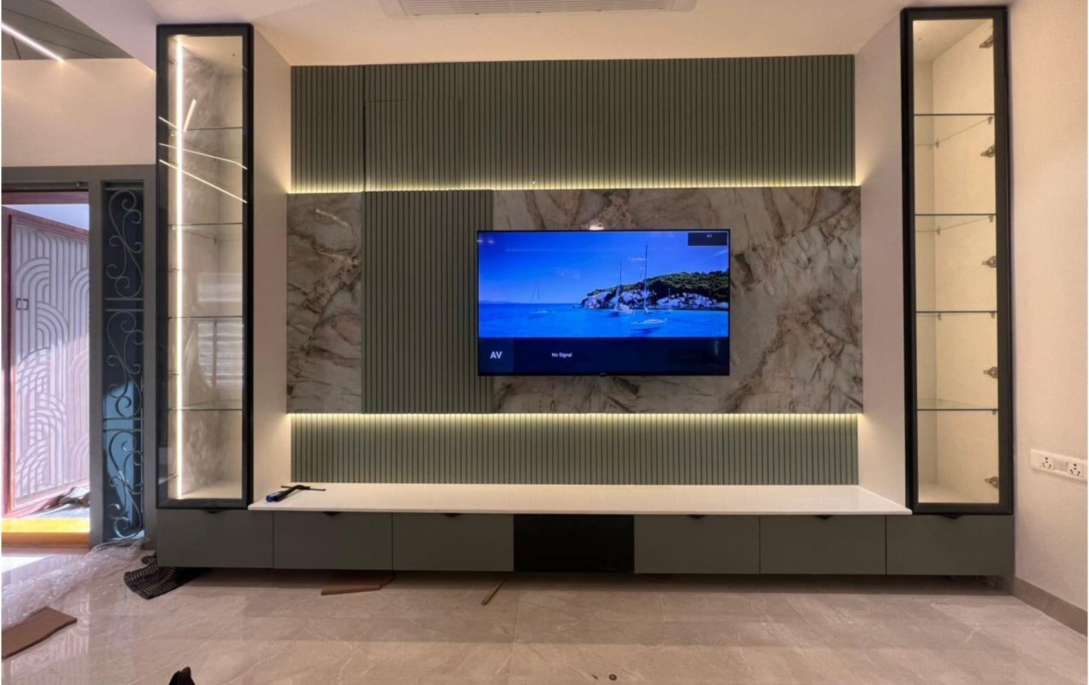 Living media wall in sage slats, marble, and glass vitrines