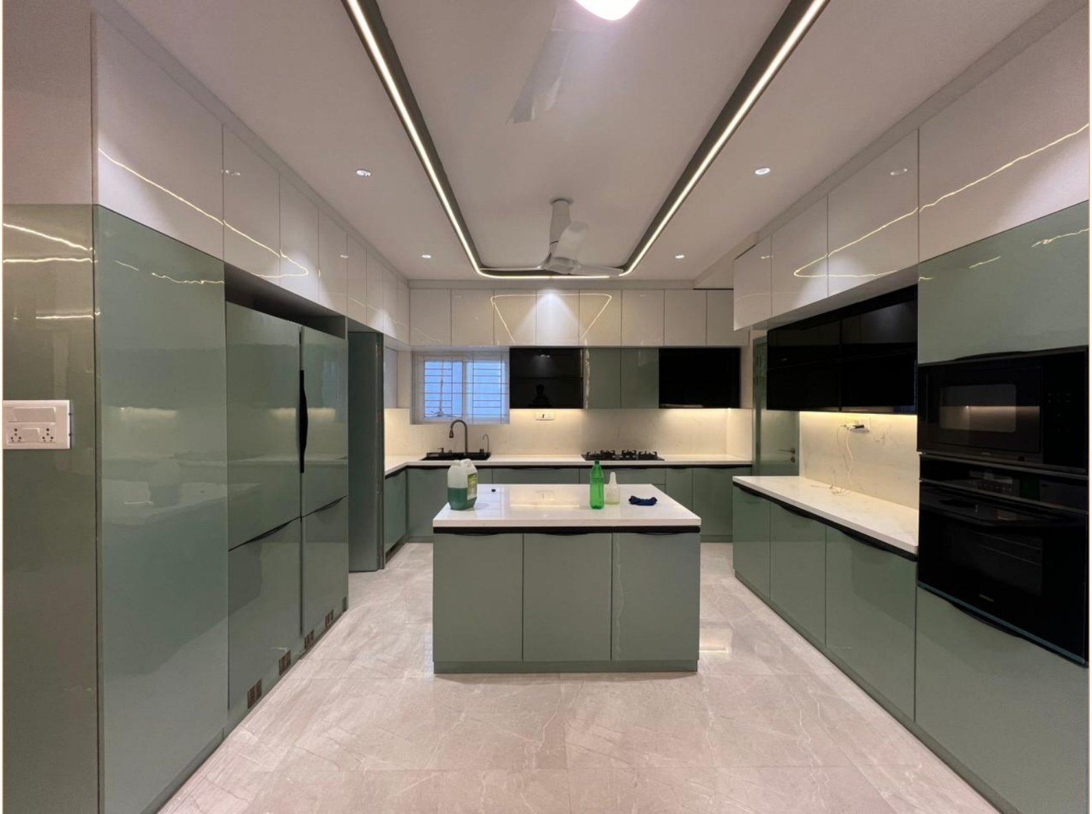 Gloss sage kitchen with island, tall units, and linear ceiling light