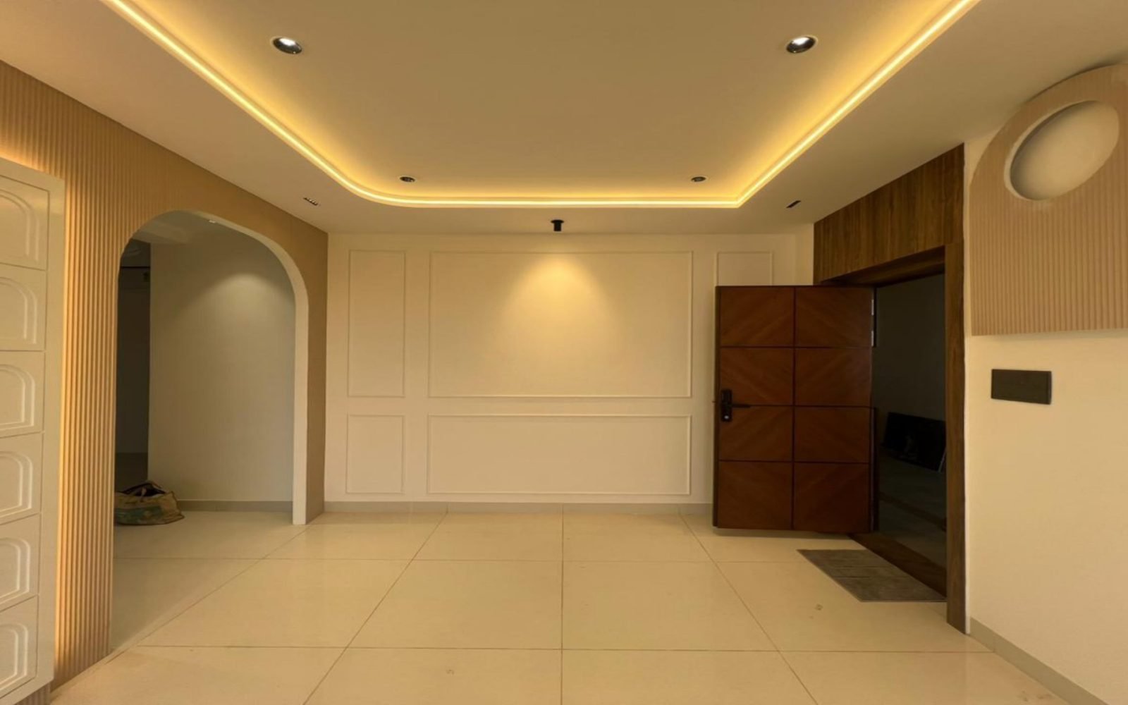 Entrance with coffered lighting, arch, and panelled wall