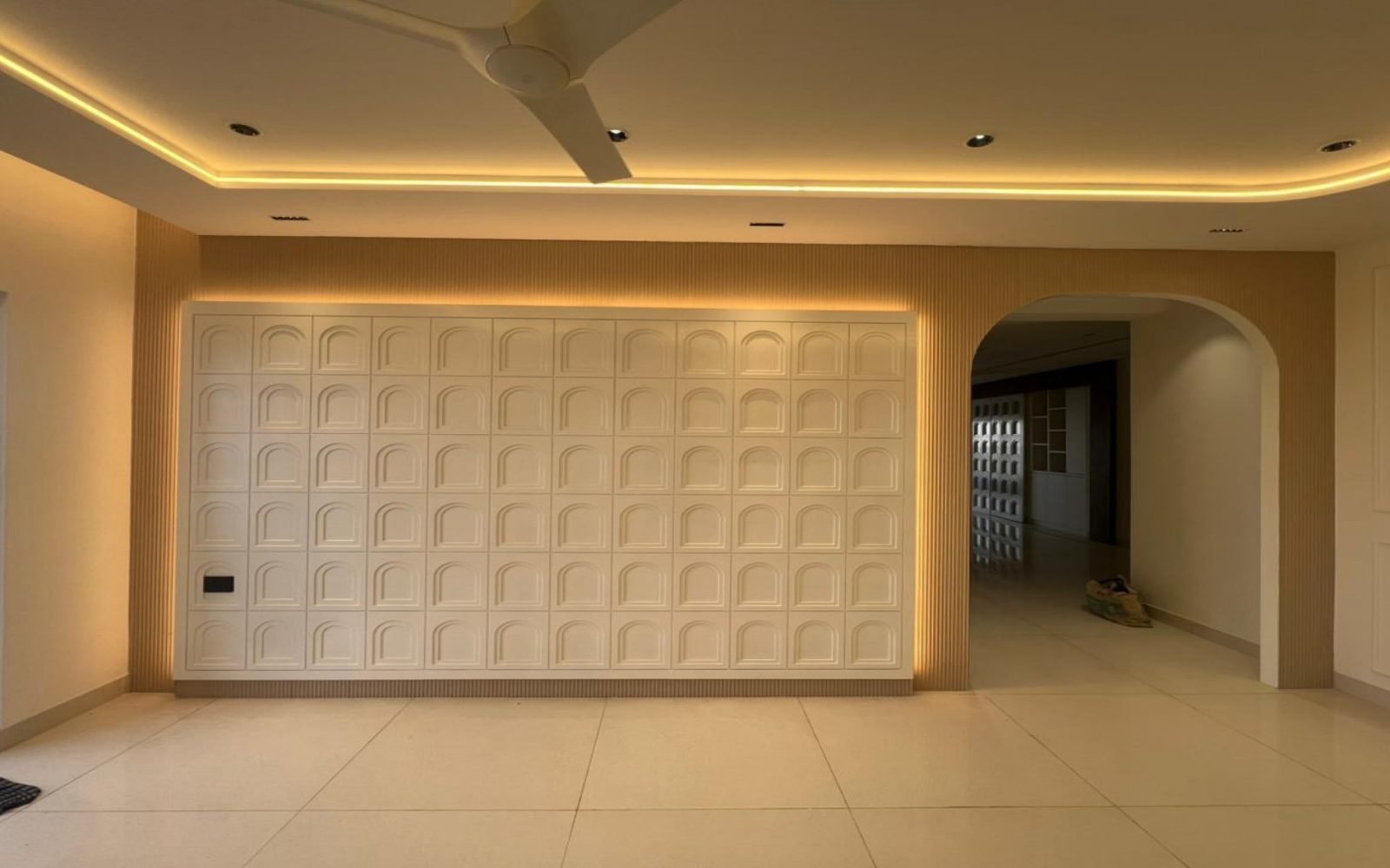 Living wall of arched millwork panels with cove lighting and a large archway