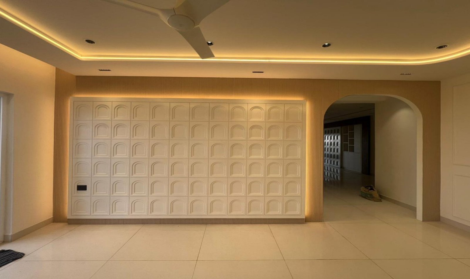 Living wall of arched millwork panels with cove lighting and a large archway