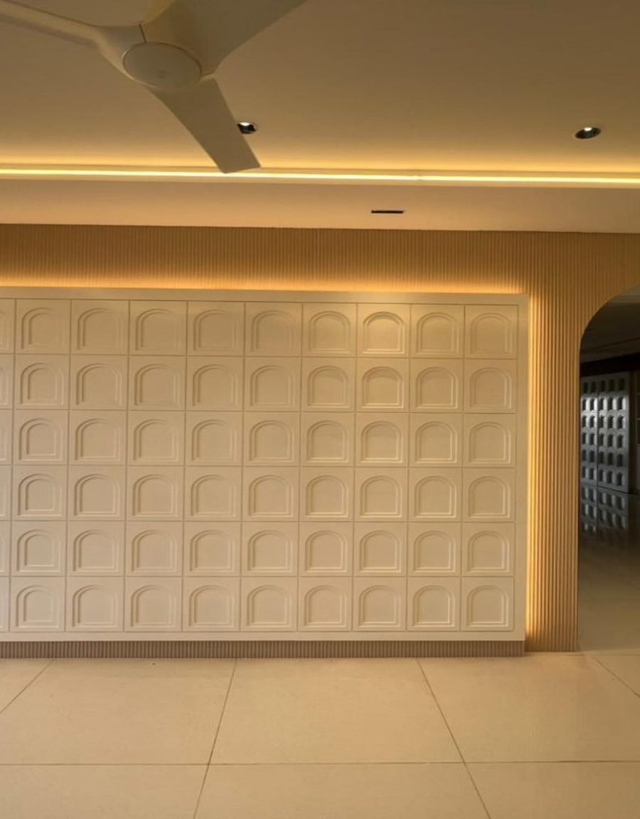 Living wall of arched millwork panels with cove lighting and a large archway