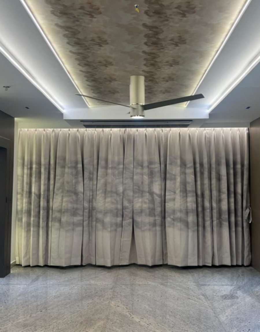 Living hall with carved wave marble, floor-to-ceiling drapery, and linear ceiling light